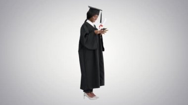 Mezun olmuş mutlu Afro-Amerikan kadın diploması ve telefonunda gradyan arka planda mesaj var..