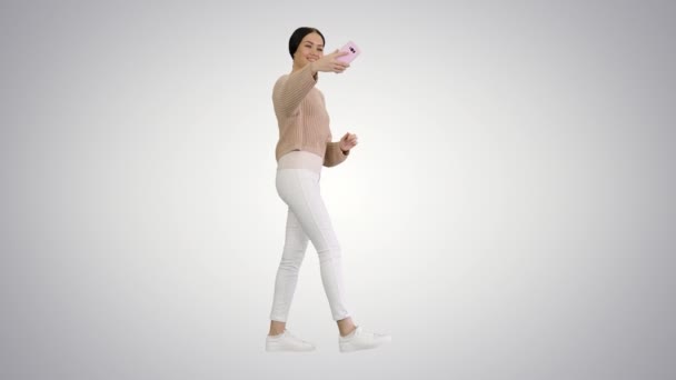 Gayri resmi giyinmiş güzel bir kadın, arka planda yürürken selfie çekiyor.. — Stok video