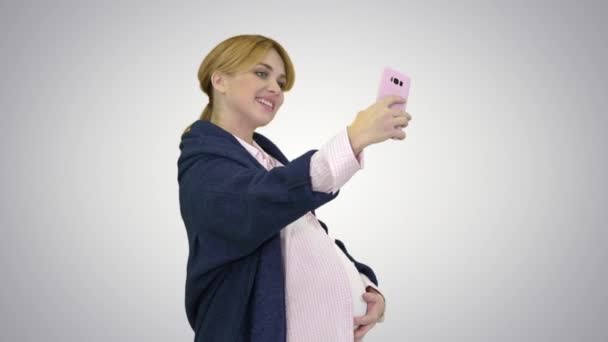 Szczęśliwa młoda ciężarna kobieta robi selfie na tle gradientu. — Wideo stockowe