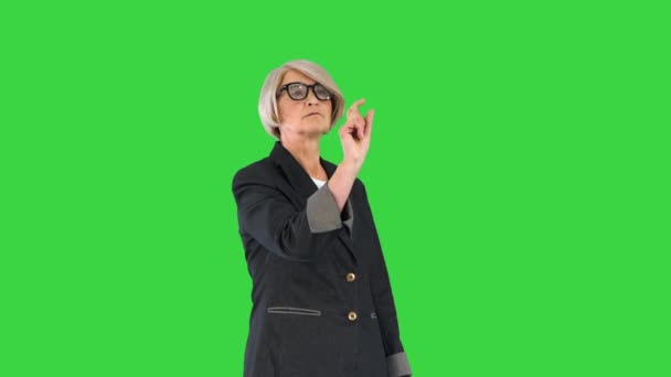 Mujer de negocios senior con gafas apuntando a los botones de una pantalla virtual en una pantalla verde, Chroma Key. — Vídeos de Stock