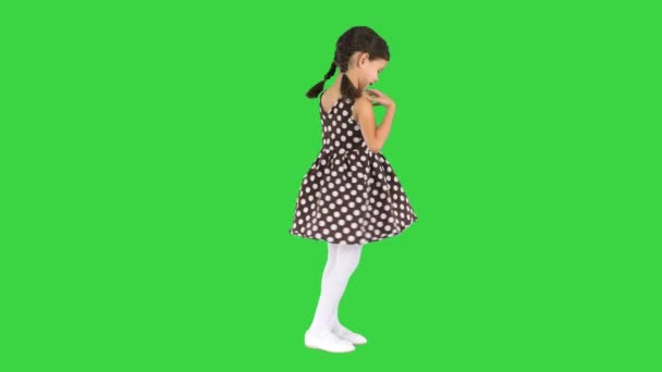 Gülümseyen küçük kız poz veriyor ve benekli elbisesini yeşil ekranda çeviriyor, Chroma Key. — Stok video