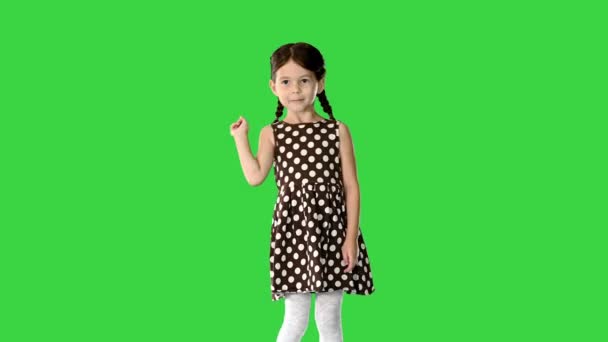 पोलका डॉट ड्रेस मध्ये लहान मुलगी नृत्य आणि ग्रीन स्क्रीनवर तिचे हात उचलून, क्रोमा की . — स्टॉक व्हिडिओ