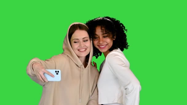 Două prietene multiculturale care pozează și îmbrățișează un selfie pe un ecran verde, Chroma Key . — Videoclip de stoc