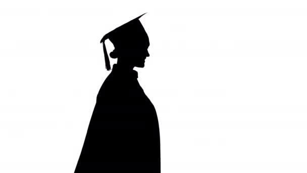 Silhouette Smiling estudiante femenina en bata de graduación caminando con su diploma. — Vídeos de Stock
