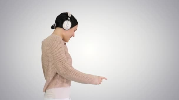 Uśmiechnięta kobieta ze słuchawkami chodzącymi i cieszącymi się muzyką na gradientowym tle. — Wideo stockowe