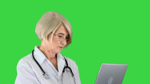 Mujer doctora senior de pie y trabajando en una computadora portátil en una pantalla verde, Chroma Key. — Vídeos de Stock