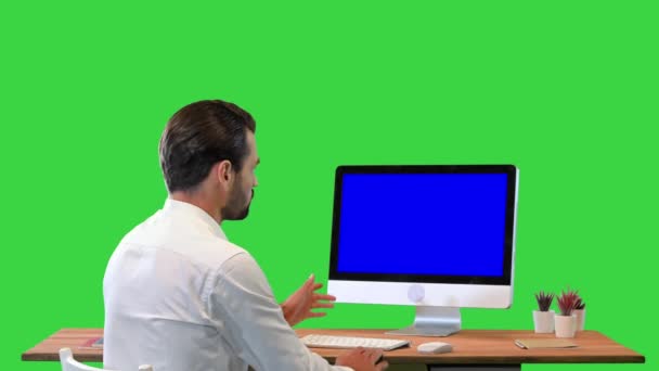 Επιχειρηματίας κάθεται δίπλα στην οθόνη και να παρουσιάσει κάτι μιλώντας στην κάμερα Mock-up οθόνη σε μια πράσινη οθόνη, Chroma Key. — Αρχείο Βίντεο