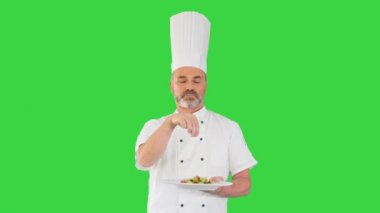 Kıdemli şef yeşil ekranda salataya baharat ekliyor, Chroma Key.
