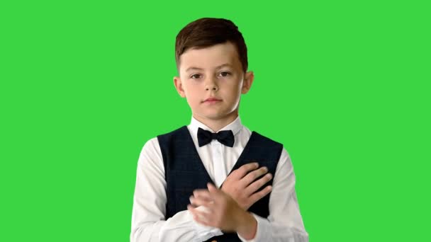 Με αυτοπεποίθηση νεαρό αγόρι με παπιγιόν και γιλέκο σταυρώνει τα χέρια του κοιτάζοντας την κάμερα σε μια πράσινη οθόνη, Chroma Key. — Αρχείο Βίντεο