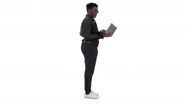 Афроамериканський бізнесмен друкує на ноутбуці і розмовляє з кимось із посмішкою, жестикулюючи на білому фоні.. — стокове відео