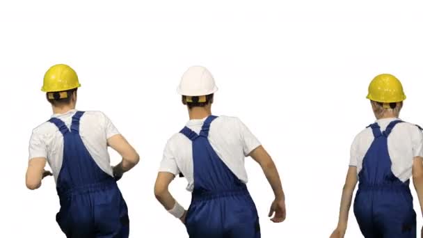 Trzech budowlańców w twardych kapeluszach tańczy plecami do kamery na białym tle. — Wideo stockowe