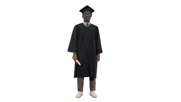 Estudiante afroamericano en bata de graduación brazos plegables con diploma mirando con una gran sonrisa a la cámara sobre fondo blanco. — Vídeos de Stock