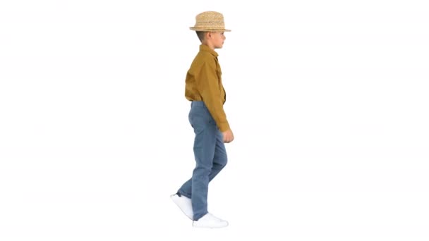 Fiú egy pólóban állítsa be a szalma kalap séta közben, és nézi a kamera fehér háttér. — Stock videók