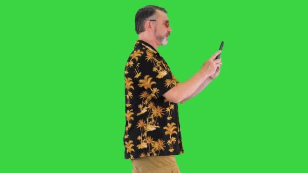 Hombre mayor turista tomando fotos por su cámara del teléfono mientras camina en una pantalla verde, Chroma Key. — Vídeo de stock