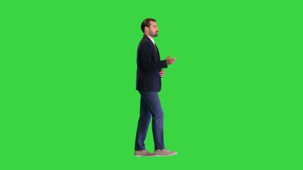 Mladý pohledný obchodník kráčí a mluví sám se sebou na zelené obrazovce, Chroma Key.