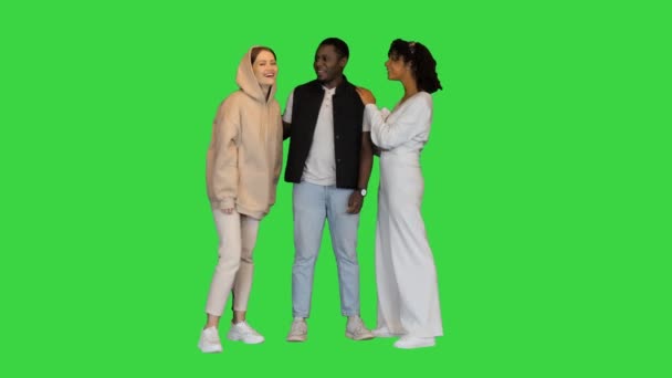 3人の幸せな混合レースの友人が緑の画面でおしゃべりし、抱き合って、クロマキー. — ストック動画
