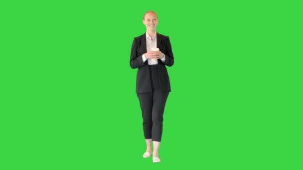 Hermosa joven rubia de negocios caminando sosteniendo una taza de café en una pantalla verde, Chroma Key. — Vídeos de Stock