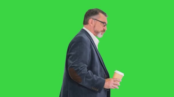 Hombre de negocios mayor caminando y sosteniendo en una mano una taza de café en una pantalla verde, Chroma Key. — Vídeo de stock