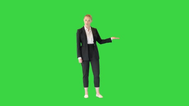 Bella donna d'affari bionda che presenta qualcosa che punta con la mano a lato su uno schermo verde, Chroma Key. — Video Stock