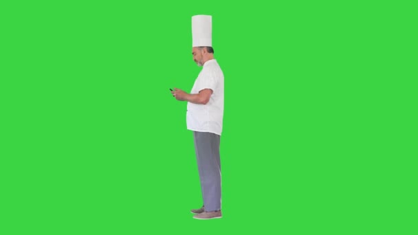 Ανώτερος σεφ με στολή χρησιμοποιώντας το κινητό τηλέφωνο σε μια πράσινη οθόνη, Chroma Key. — Αρχείο Βίντεο