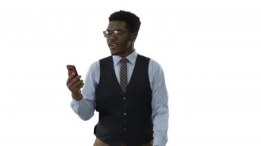 Gülümseyen Afrikalı Amerikalı işadamı elinde cep telefonuyla beyaz arka planda yürürken video görüşmesi yapıyor..