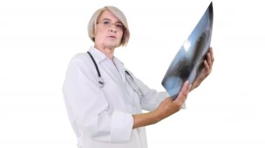 Kıdemli kadın doktor florografiyi inceliyor ve sadece beyaz arka planda kameraya bakıyor..