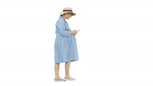 Young pregnant woman in trendy hat walking and using her phone on white background. — Stock Video