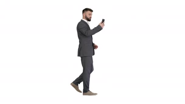 Hombre de negocios guapo caminando y grabando vlog en su teléfono sobre fondo blanco. — Vídeos de Stock