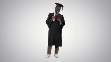 Mezuniyet cüppesi giymiş gülümseyen Afro-Amerikan erkek öğrenci. Grafik arka planda telefonda diploma mesajı yazıyor..