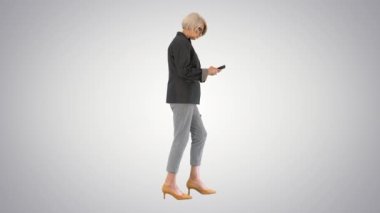 Seçkin bir son sınıf öğrencisi, arka planda yürürken akıllı telefon kullanıyor..