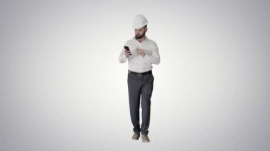 Gradyan arkaplanda yürüyen ve akıllı telefon kullanan bir mühendis.
