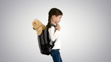 Sırt çantasında oyuncak ayıyla okula yürüyen tatlı küçük bir kız var..