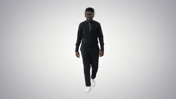 Fiatal afro-amerikai férfi zenét hallgat a fejhallgató séta közben gradiens háttér. — Stock videók