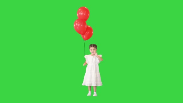 Adorable niña se aferra firmemente a un gran montón de globos de helio caminando en una pantalla verde, Chroma Key. — Vídeo de stock
