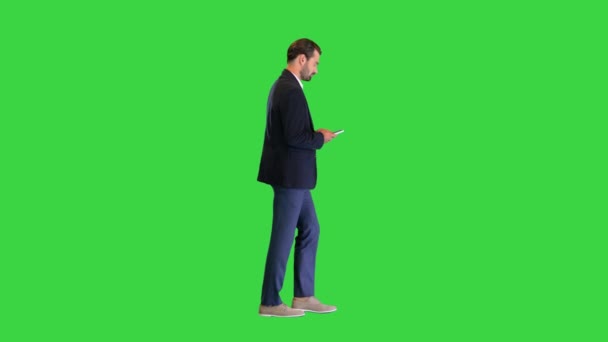 Jonge zakenman loopt en sms 't op zijn telefoon op een groen scherm, Chroma Key. — Stockvideo