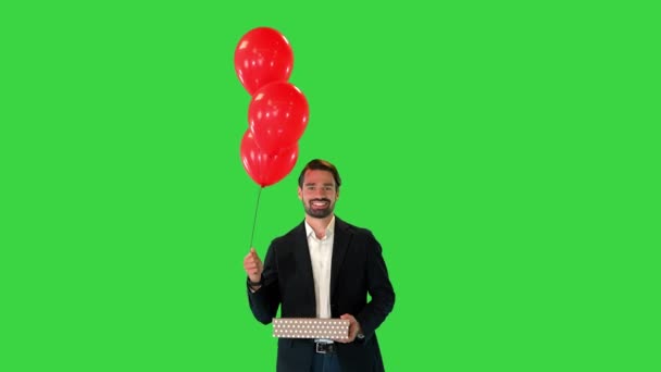 Beau mec dans un costume élégant avec un coffret cadeau et des ballons marchant sur un écran vert, Chroma Key. — Video