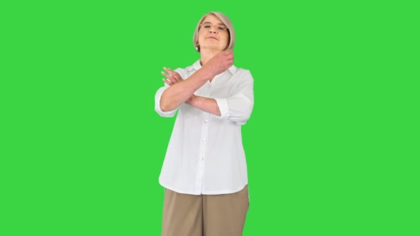 Ηλικιωμένη γυναίκα στέκεται με σταυρωμένα χέρια σε μια πράσινη οθόνη, Chroma Key. — Αρχείο Βίντεο