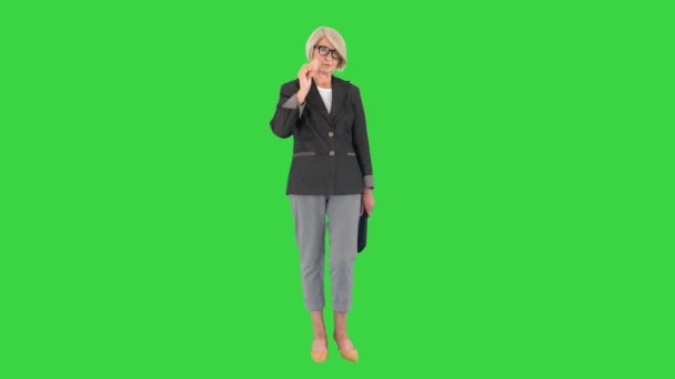 Strikt allvarlig äldre kvinna står och tittar på kameran på en grön skärm, Chroma Key. — Stockvideo