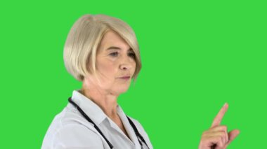 Sağlık, tıp ve teknoloji konsepti - Kıdemli kadın doktor bir şeye işaret ediyor veya yeşil ekrandaki hayali düğmelere basıyor, Chroma Key.
