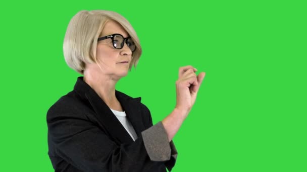 Mujer formal senior en gafas usando pantalla táctil virtual en una pantalla verde, Chroma Key. — Vídeos de Stock