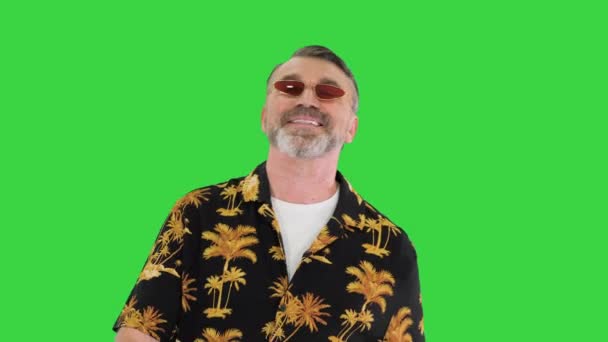 緑の画面、クロマキーの上を歩くサングラスのシニア男性観光客. — ストック動画