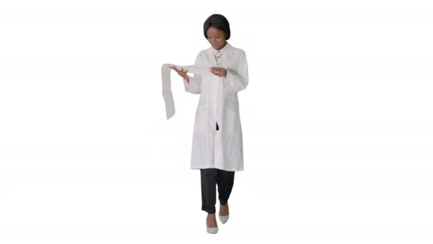 Усміхнена афроамериканська жінка-лікар читає кардіограму на білому тлі . — стокове відео