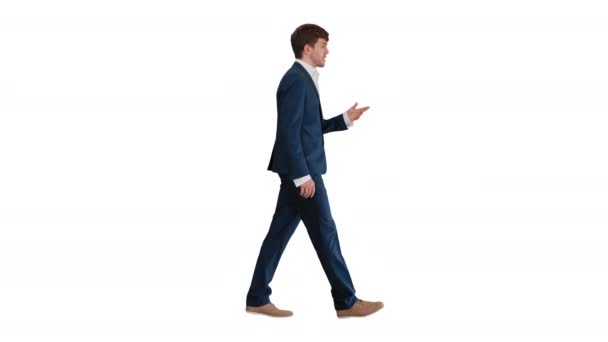Uomo d'affari che cammina e spiega qualcosa alla macchina fotografica su sfondo bianco. — Video Stock