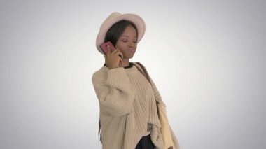 Güzel Afro-Amerikan kadın örgü süveter ve beyaz şapkalı telefonuna gradyan arka planda cevap veriyor..