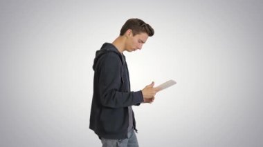 Genç adam gradyan arkaplanda yürürken dijital tablet kullanıyor.