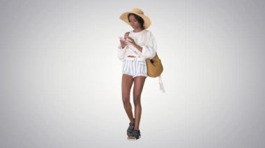 Hasır şapkalı gülümseyen Afro-Amerikan kadın telefonuyla grafiksel arka planda mesajlaşıyor..