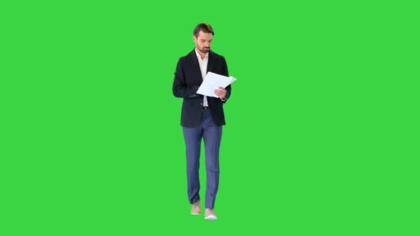 緑の画面、クロマキーを歩いている間に文書を読む深刻な若いビジネスマン. — ストック動画