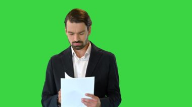 Genç bir iş adamı yeşil ekran, Chroma Key 'deki belgelere bakıyor..