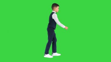 Papyonlu ve yelekli küçük bir çocuk elini yeşil ekranda sallıyor, Chroma Key.
