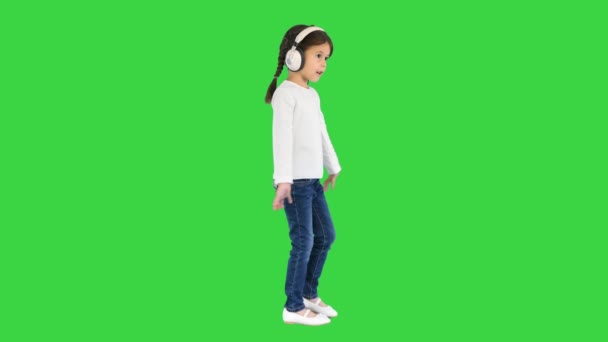 Eccitato bambina vestita di bianco ascoltando la musica in cuffia e cantando insieme su uno schermo verde, Chroma Key. — Video Stock